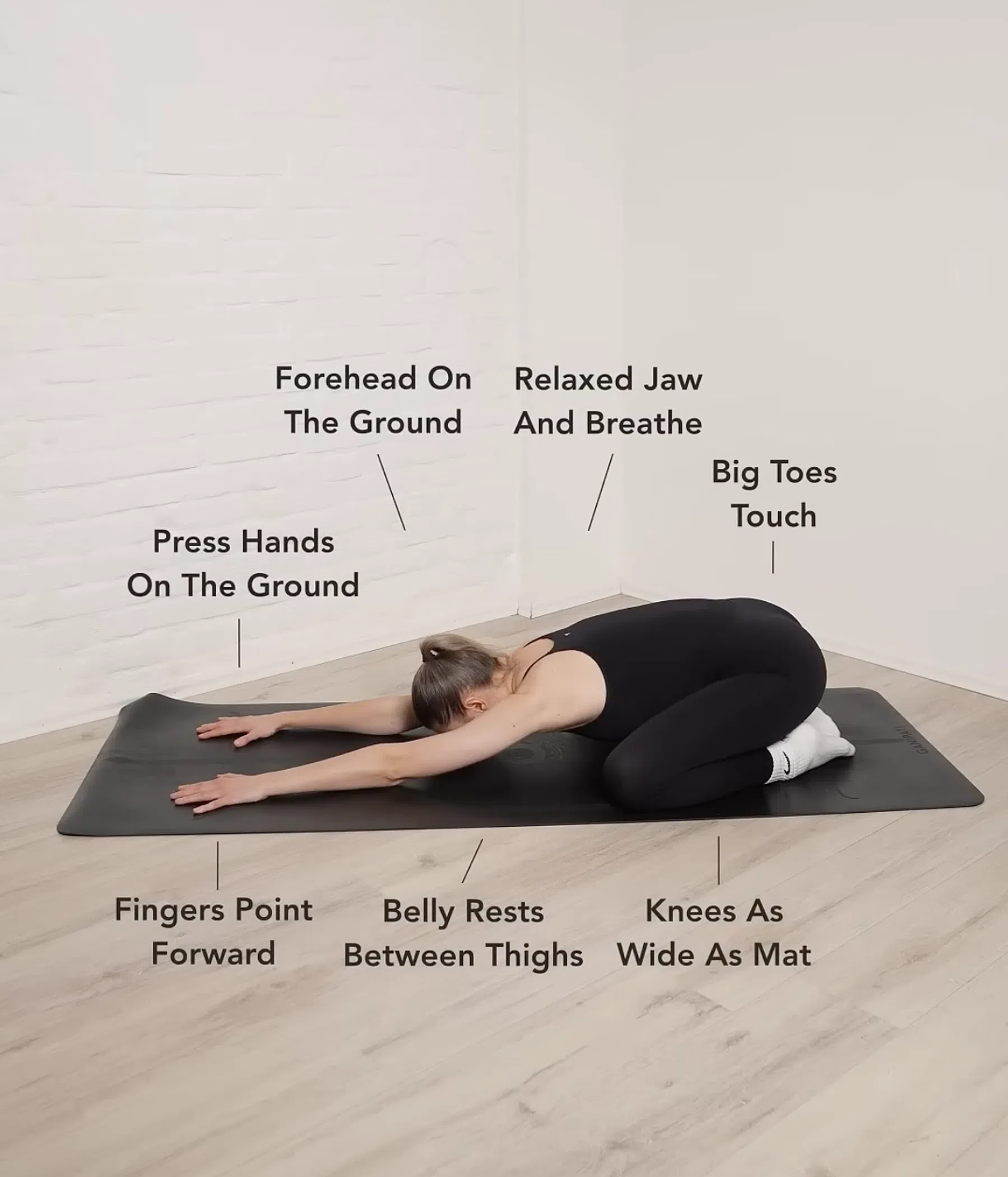 Vrouw ligt gestrekt in de child pose op een yogamatje.